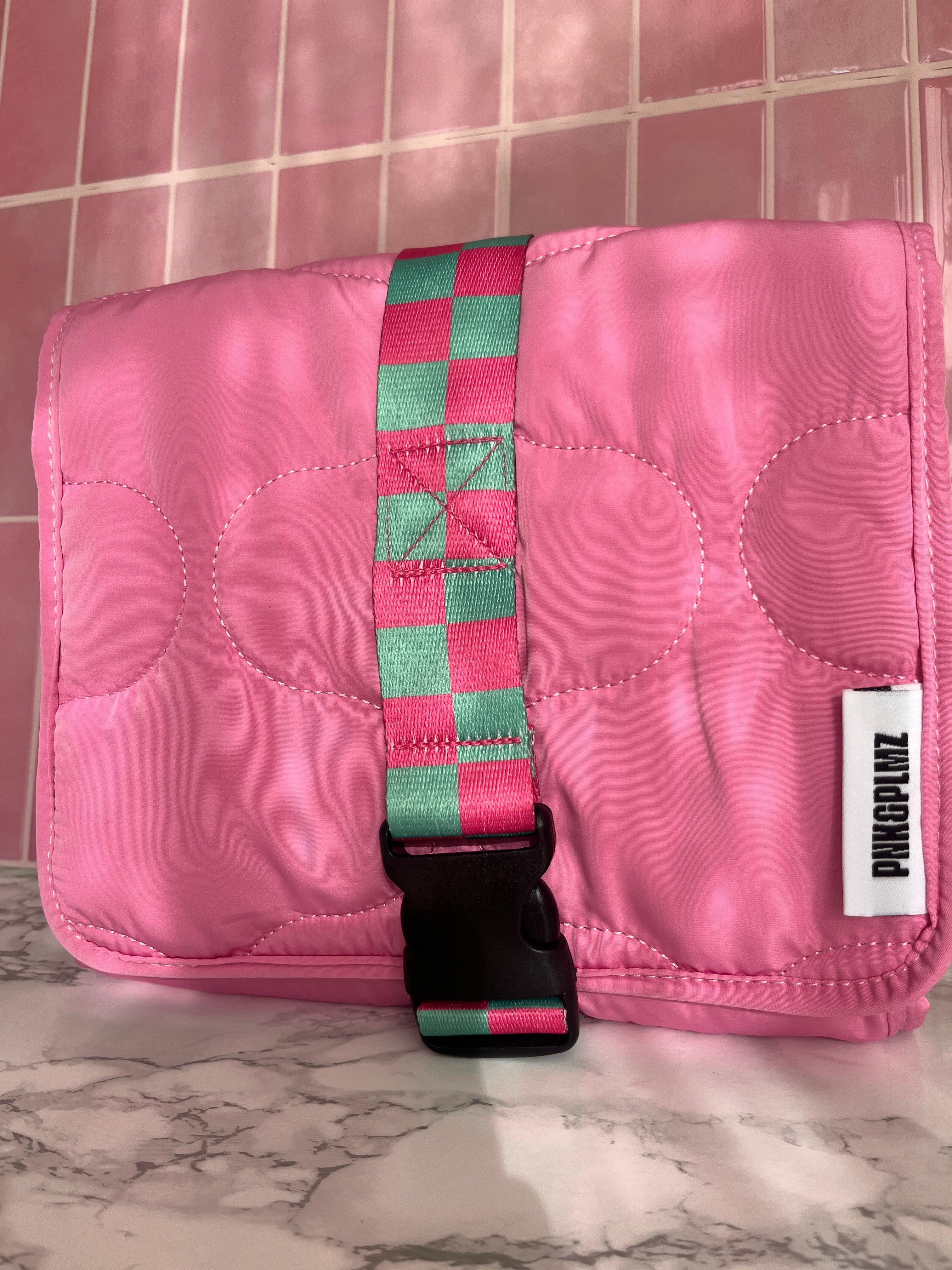 Roze travel sleeve met groene strap – lifestyle opname in roze omgeving