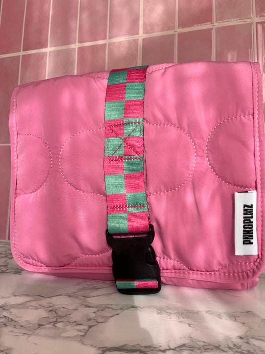 Roze travel sleeve met groene strap – lifestyle opname in roze omgeving